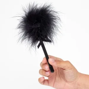 Hand hält einen schwarzen Stift mit flauschigem, pelzartigem Aufsatz.