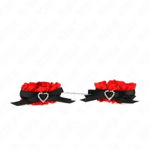 Rote und schwarze Handfesseln mit Herzverzierung und Kette, auf weißem Hintergrund.
