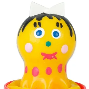 Gelbe Gummifigur mit blauen Augen, rosa Punkten und schwarzem Haar, trägt eine weiße Schleife.