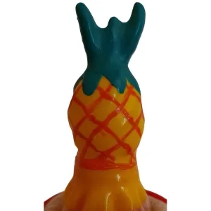 Bunte Plastikfigur in Form einer Ananas mit grünem Blattwerk und orangefarbenem Gittermuster.