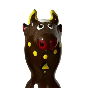 Keramikfigur eines braunen Stiers mit gelben Hörnern und Punkten, roter Schnauze und großen Augen.