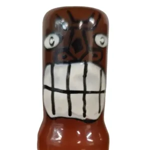 Ceramic figure with a grim facial expression, large eyes and a wide, jagged mouth.