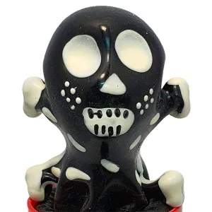 Schwarze Figur mit weißen Augen und Zähnen, die wie ein Skelett aussieht, auf rotem Sockel.