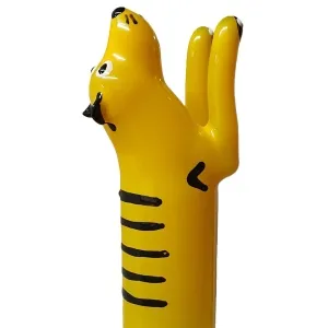Yellow, cartoon-like sculpture of an animal with black stripes and raised paws, viewed from the side.