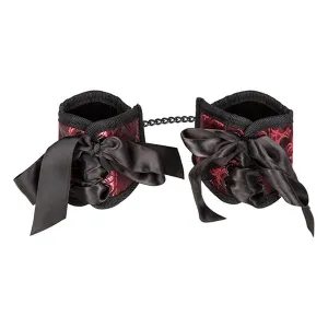 Red and black handcuffs with bows and chain, decoratively designed.