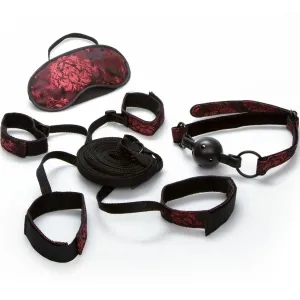 Schwarzes und rotes Bondage-Set mit Augenmaske, Fesseln, Ballknebel und Seil auf weißem Hintergrund.