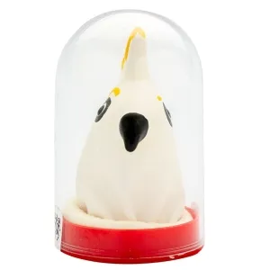 White clay figure of a bird with a black beak and yellow details, under a transparent dome on a red base.