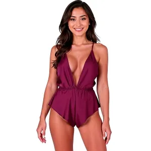 Woman in a burgundy, low-cut jumpsuit with spaghetti straps, smiling against a white background.